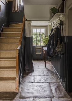 an entry way with stairs and clothes hanging on the wall