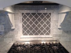 a stove top oven sitting in a kitchen next to a wall with a tile design on it