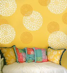 a white couch sitting in front of a yellow wall with circles on it's back