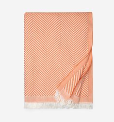 an orange and white herringy blanket with fringes on the edges, folded in two rows