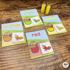 four cards with pictures of oranges and red bugs on them sitting on a wooden table