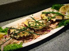 a white plate topped with lettuce and other food on top of a counter