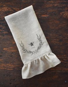 a linen napkin with a bee embroidered on it sitting on top of a wooden table