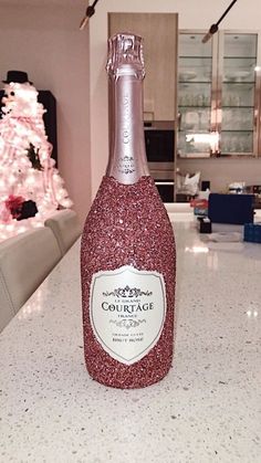 a bottle of champagne sitting on top of a counter next to a pink christmas tree