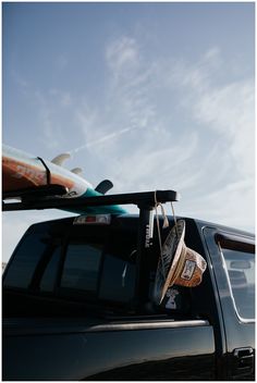 a truck with two surfboards on top of it's roof rack and another vehicle in the back