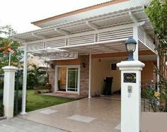 a house that has a white pergolan over the front door and side entrance