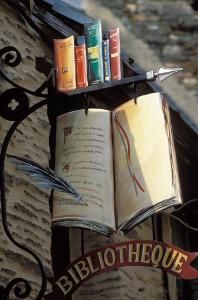 an open book sitting on top of a metal shelf next to a sign that reads bibliote