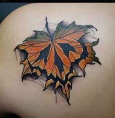 an orange and black leaf tattoo on the back of a woman's shoulder