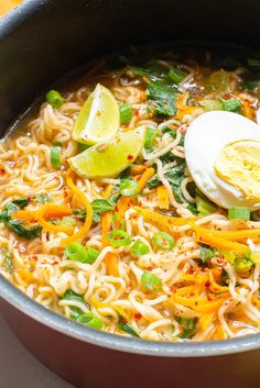 a pot filled with noodles and vegetables next to an egg