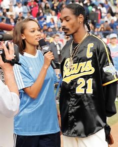 a man and woman standing next to each other in front of a crowd with microphones