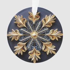 a circular ornament with gold and blue designs on the front, hanging from a white ribbon