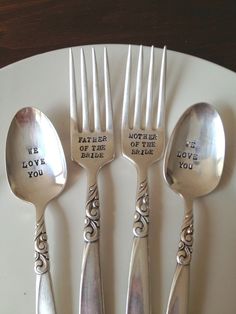 four silver spoons and two forks with words written on them sitting on a white plate