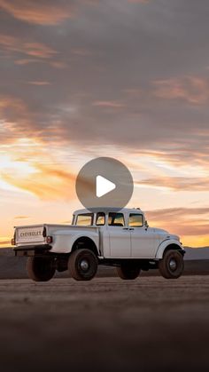 an old pick up truck is parked in the desert at sunset, with clouds overhead