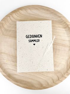 a wooden plate with a card on it that says gedanken sammelr