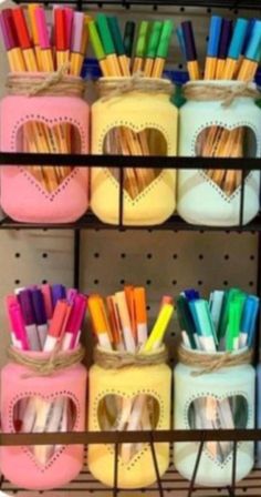 several jars filled with different colored pens and pencils on top of a shelf next to each other