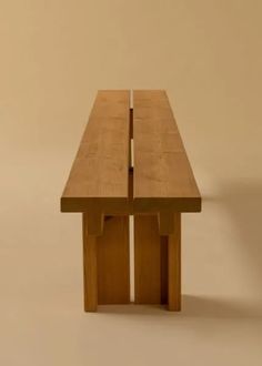 a wooden table sitting on top of a white floor next to a brown wall with two legs