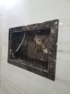 a black and white marble bathroom with a square shaped mirror on the wall above it