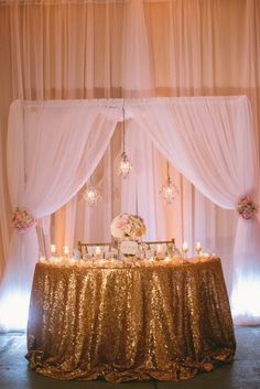 a gold sequin covered table with white drapes