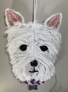 a white dog ornament hanging on a wall next to a potted plant