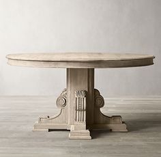 an oval dining table with carved details on the top and base, sitting on a wooden floor