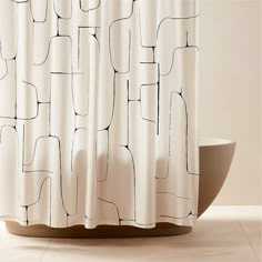 a white shower curtain with black lines on it and a bowl in the foreground