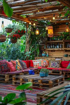 an outdoor living area with wooden pallets and colorful pillows on the couches, potted plants and hanging lights