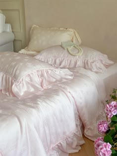 a white bed with pink flowers on the side and a pillow sitting on top of it