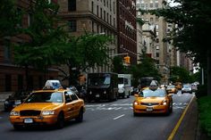 taxi cabs driving down the street in new york city