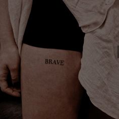 a woman's leg with the word brave tattooed on her left thigh and right leg behind her