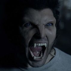 a man with his mouth open and teeth wide open in the dark, looking like he is screaming