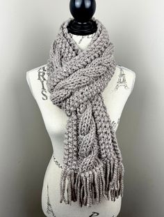 a gray knitted scarf sitting on top of a mannequin