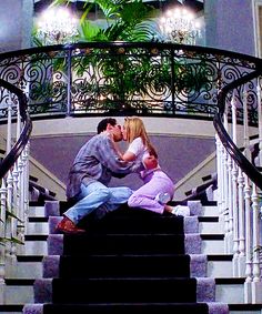 a man and woman kissing on the stairs