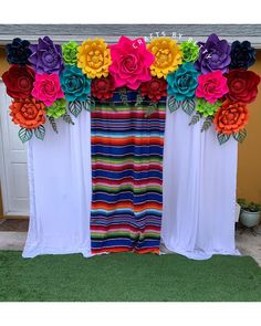 colorful paper flowers are hanging from the top of curtains