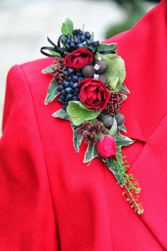 a red suit with flowers and berries on it's lapel pin, is seen here