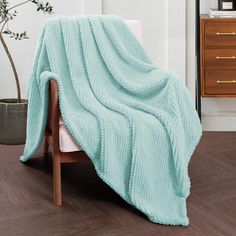 a blue blanket sitting on top of a wooden chair next to a potted plant