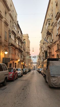 an empty city street with cars parked on both sides and buildings in the back ground