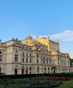 an ornate building with many windows and flowers in the foreground on a sunny day