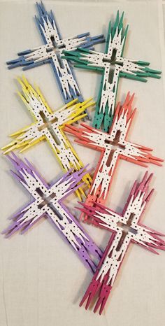 four crosses made out of popsicle sticks on a white cloth with holes in the middle