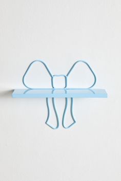 a wall mounted shelf with a bow on it's top and two hooks attached to the side