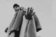 black and white photograph of two people standing next to each other with gloves on their shoulders