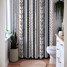 a white toilet sitting next to a shower curtain with black and white designs on it