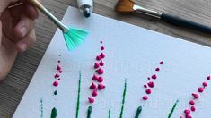 someone is painting flowers on a piece of paper with acrylic paint and brush