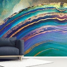 an abstract wall mural in a living room with blue, green and gold paint on it