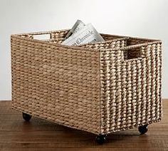 a wicker basket sitting on top of a wooden table next to a magazine holder