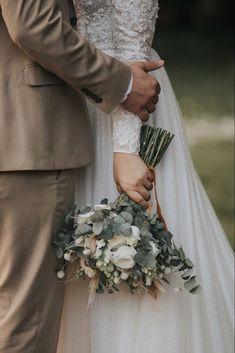 the bride and groom are holding each other's hands while they stand close together