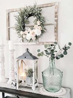 a table topped with vases filled with flowers next to a mirror and candle holder