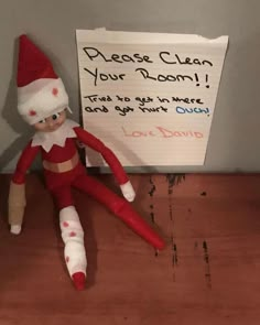 an elf doll sitting next to a sign that says please clean your room