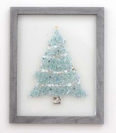 a small glass christmas tree in a gray frame on a white wall with silver trim