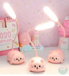 three pink kitty lamps sitting on top of a table