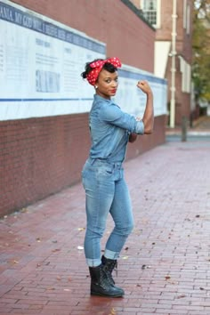 a woman in overalls and a red bandana is posing for the camera with her fist up